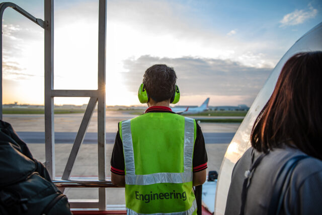 Back of engineer mechanic ground crew worker at the airport looking airplane on runway