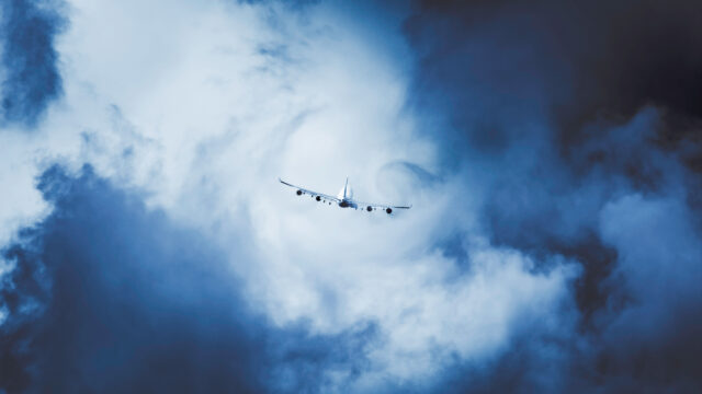 A large plane taking off through clouds creating a swirl of turbulence. Stormy day and bad weather conditions