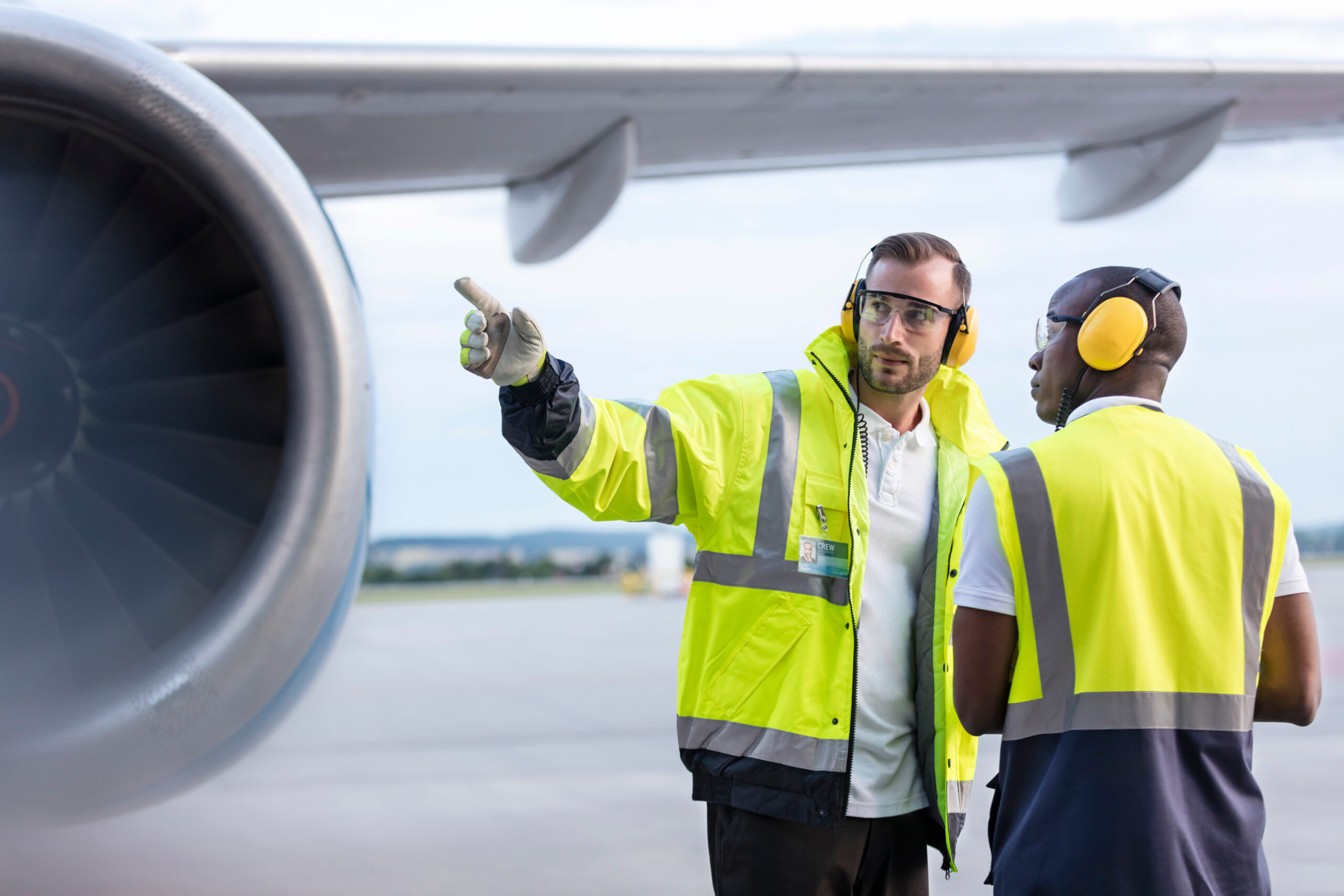 Air traffic control ground crew workers talking near airplane on airport tarmac
