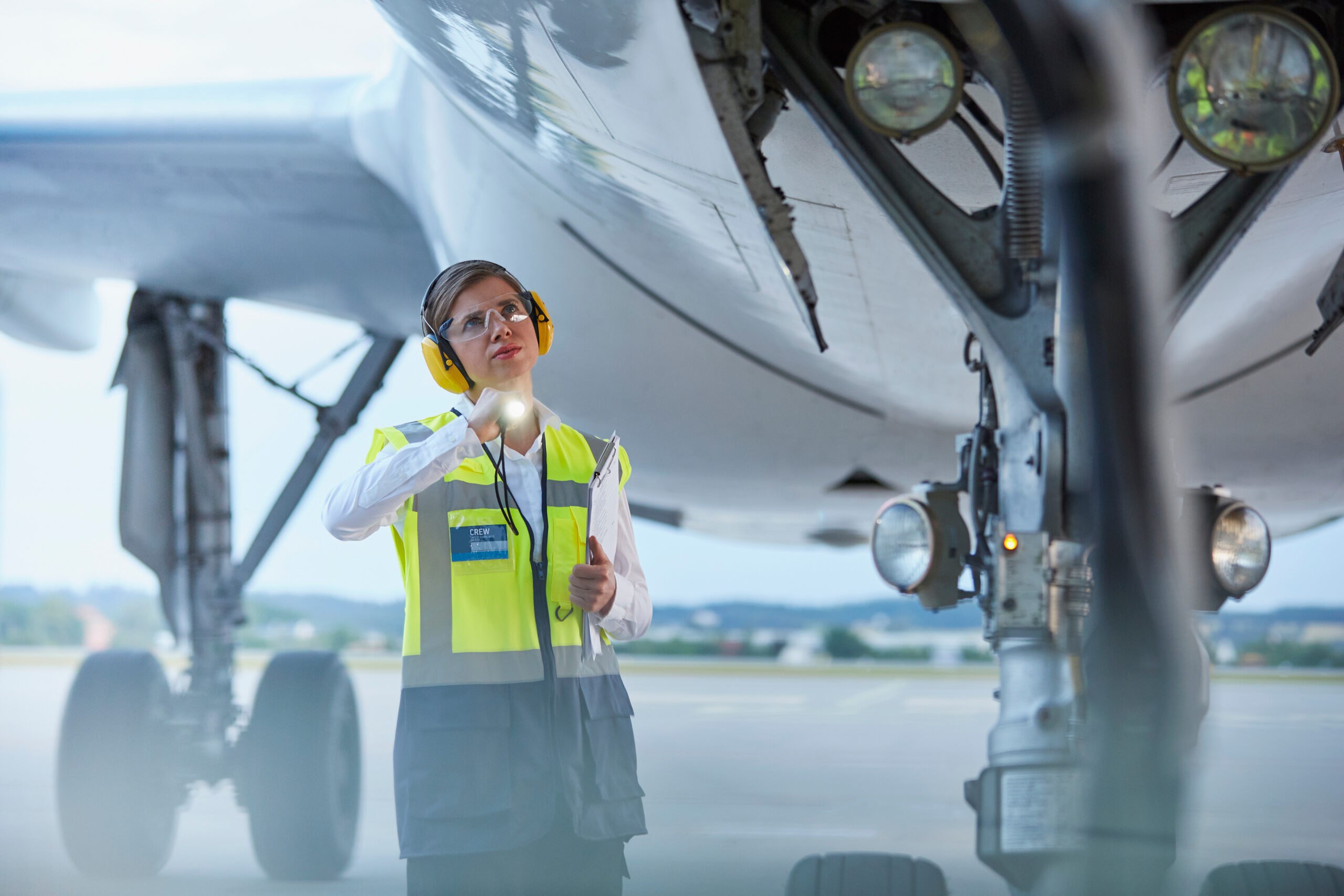 Ground crew worker under airplane with flashlight on airport tarmac